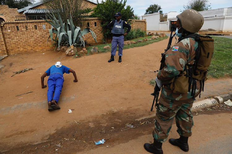 A policeman instructs a man to do push-ups during an operation in Eldorado Park, on the fourth day of a nationwide lockdown.