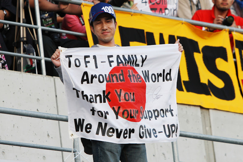 болельщик на трибунах Сузуки с японским флагом со словами благодарности на Гран-при Японии 2011