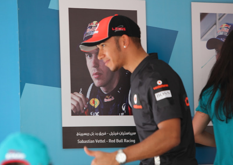 Льюис Хэмилтон на фоне плаката Себастьяна Феттеля на автограф-сессии Гран-при Абу-Даби 2011