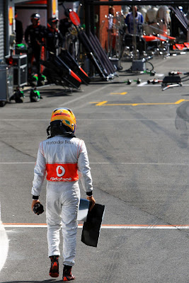 Льюис Хэмилтон несет обломок переднего крыла McLaren на Гран-при Бельгии 2012