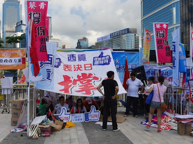 people sitting in the shade of an outstretched banner