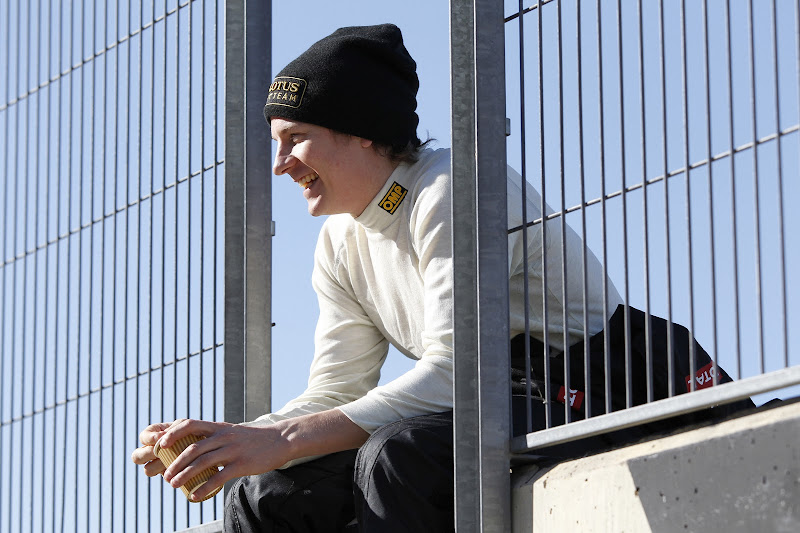 улыбающийся Кими Райкконен сидит на заборе на тестах в Валенсии 23 января 2012