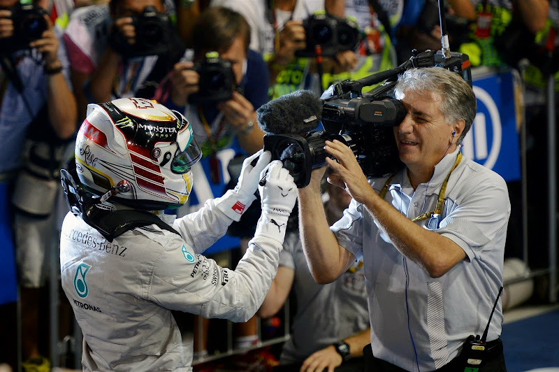 Льюис Хэмилтон ставит автограф на объективе телевизионной камеры на Гран-при Абу-Даби 2014