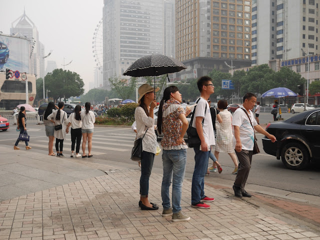 woman holding an umbrella at a street intersection in Changsha