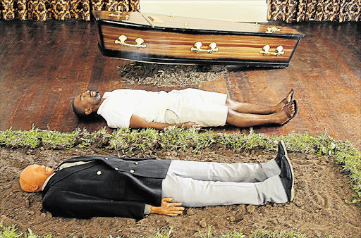 TOUCHING THE EDGE: Lovedale College fine arts lecturer Sonwabiso Ngcai lies alongside an image he made of himself in one of his installations, currently up at the Ann Bryant art gallery, in which he examines the rituals, beliefs and myths surrounding twins in Xhosa culture. This piece shows how a surviving twin is meant to lie in his dead twin’s grave for a few minutes ahead of the burial. Picture: SUPPLIED