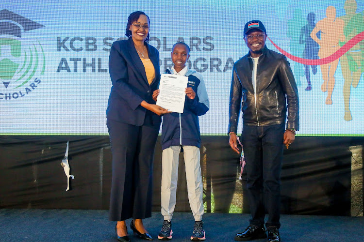 KCB Bank Managing Director Kenya, Annastacia Kimtai hands over an education scholarship contract to Chantelle Chepkorir, as the CS Sports Ababu Namwamba cheers on.