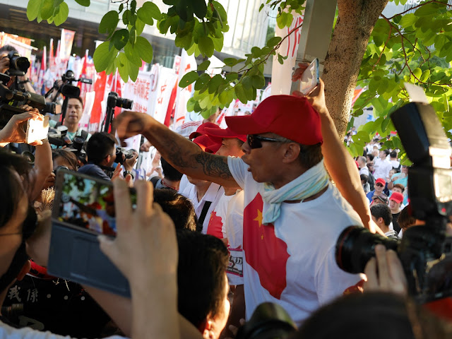 man wearing shirt with a Chinese flag yelling at people