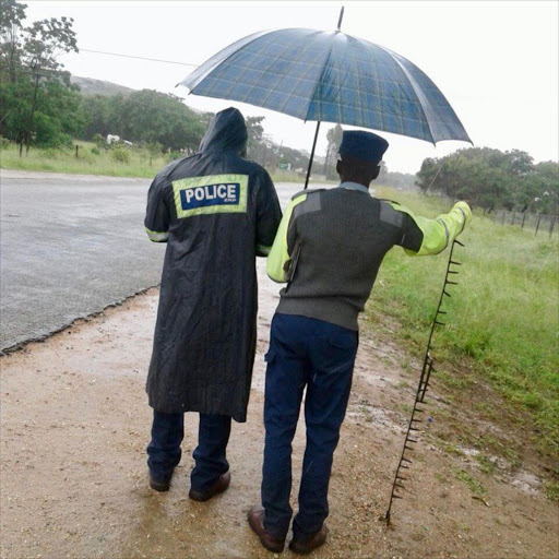 Police wait by the roadside with a spiked iron bar in Harare. Image by: Pamela Keletso