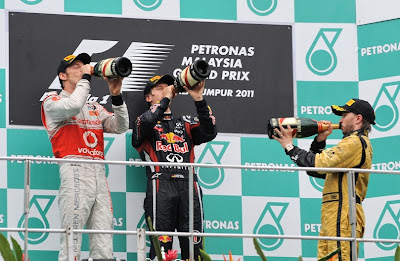 Дженсон Баттон, Себастьян Феттель и Ник Хайдфельд пьют шампанское на подиуме Куала-Лумпура на Гран-при Малайзии 2011