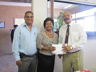 Reggie and Bronwynne Moses from University Booksellers handing a tee-shirt to the Principal Tommy Wilson