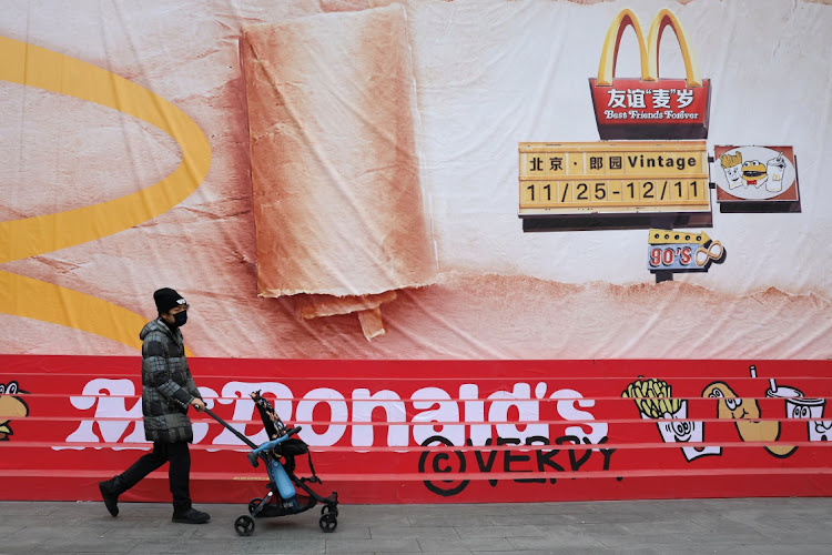 A person pushes a stroller and walks past a poster for McDonald's themed exhibition in Beijing on December 4 2023. Picture: REUTERS/TINGSHU WANG