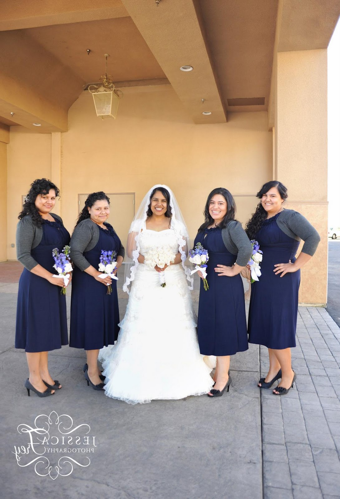 Tea length purple bridesmaid dresses with gray cover up and purple bouquets