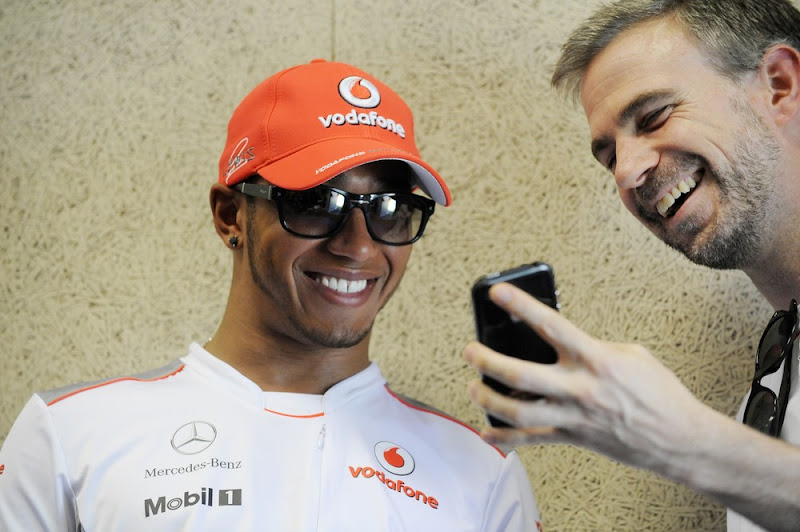 инженеру показывает что-то смешное на своем телефоне Льюису Хэмилтону на Гран-при Европы 2012