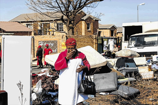 WHAT NOW? Dimakatso Koee, 65, with her seven-month-old granddaughter, Bophelo, on her back, was evicted from her daughter's rented townhouse in Honeydew, west of Johannesburg, yesterday. More than 50 families were forcibly removed from complexes in the area, allegedly for failing to pay rent since 2012
