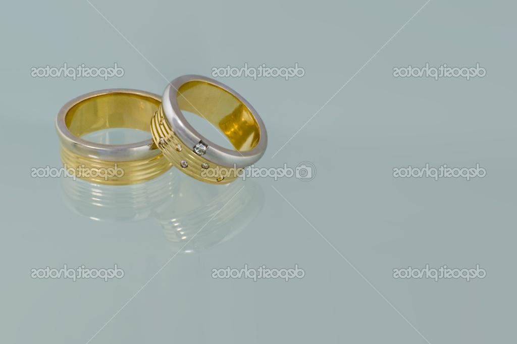 Gold wedding rings with diamonds reflected on a surface