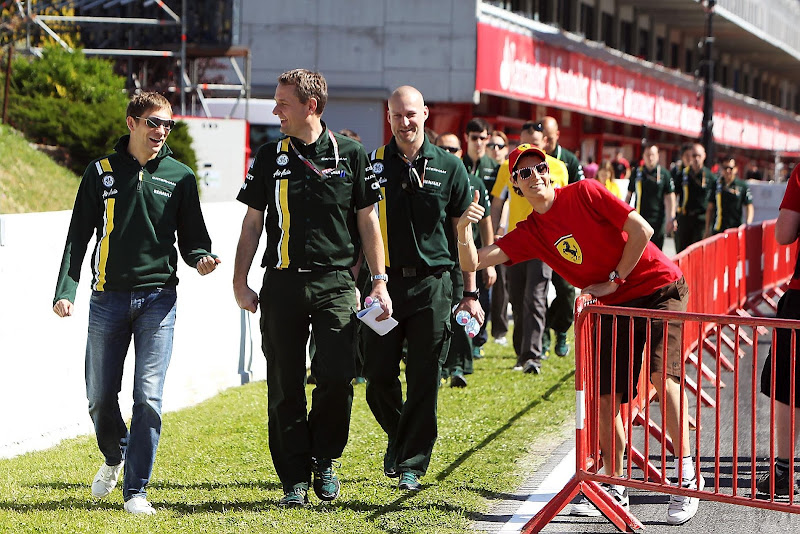болельщик Ferrari фотографирется на фоне Виталия Петрова и механиков Caterham на Гран-при Испании 2012