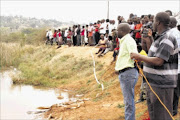 SHOCKED: Community members of  Thohoyandou, Limpopo, look on as police search for two bodies in a dam. PHOTO: BENSON NTLEMO