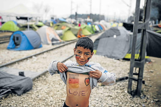 DESTINATION EUROPE: A child shows his chest painted in the colours of the German flag at a makeshift camp at the Greek-Macedonian border Picture: REUTERS