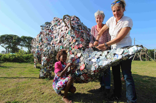 ART FROM TRASH: Liyabona Mkalipi, 11, puts the finishing touches on a giant rhino made by Port Alfred township residents Hilly Bijl, right, and international waste artist Maria Koijck Picture: DAVID MACGREGOR