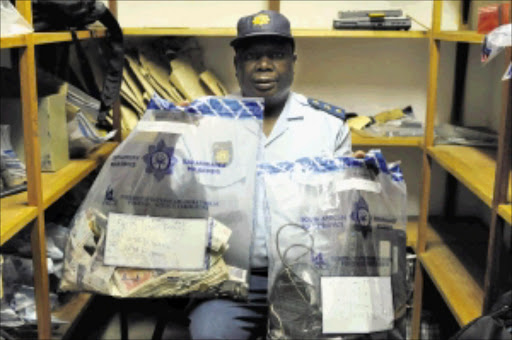 SEIZED: Captain Philemon Khorombi with money, drugs and other things found by police during a raid at a house in Eldorado Park. Pic. Peter Mogaki. 23/11/2009. © Sowetan.