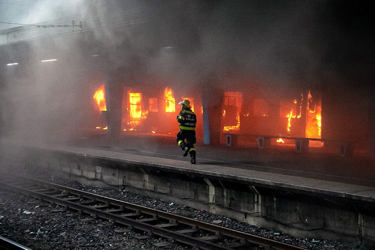 A fireman sprints along a platform at Cape Town's central railway station as a train burns. Arson attacks have reduced the size of the city's train fleet by more than half since 2015.