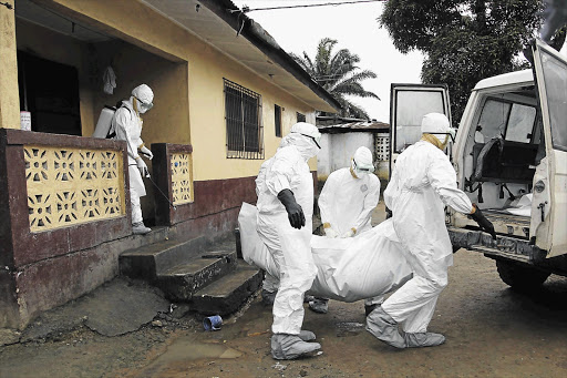 THE MOUNTING TOLL: Liberian nurses remove an Ebola victim's body from a home on the outskirts of Monrovia, the capital. The World Health Organisation has declared Ebola a global health emergency. About 1000 people have been killed by the disease since the first cases were reported in Liberia, Sierra Leone, Guinea and Nigeria about a month ago