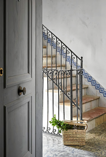 The stairwell features a cast-iron balustrade, stone treads, and Mallorcan wall tiles.