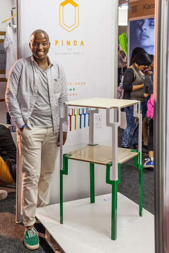 Durban designer Siyanda Mbele of Pinda shows how the side tables he designed can be cleverly stacked together to create a shelving unit.