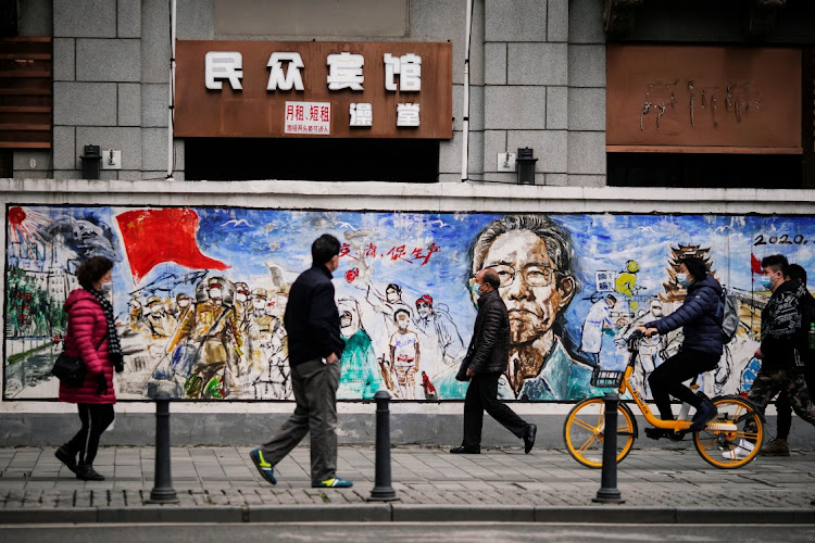 People wearing face masks walk on a street almost after the global outbreak of the Covid-19 in Wuhan, Hubei province,