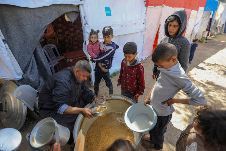 Citizens queue for food that is cooked in large pots and distributed for free during war-time on March 10, 2024 in Rafah, Gaza.