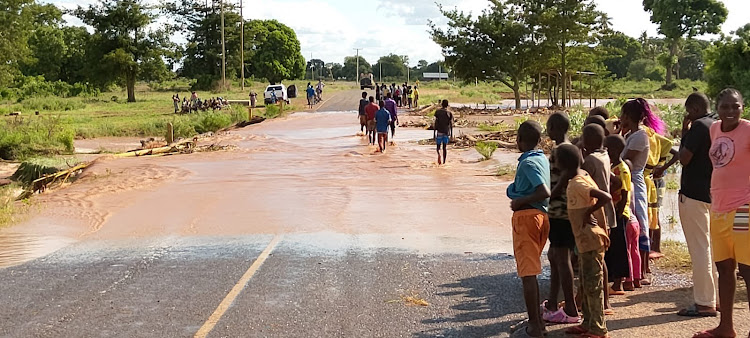 Children stand by the flooded Malindi-Sala Gate Road at Madumadu village as others wade through the water on Friday, May 3, 2024.