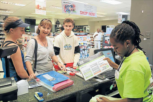 PREPARING FOR SCHOOL: Meredith Judd with her son, Matthew Judd, and daughter Ashleigh Judd buy stationery at Waltons stationers in Vincent yesterday Picture: SINO MAJANGAZA