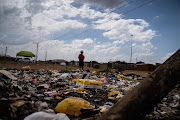 Nomsa Khumalo walks by rubbish that has been dumped in Ward 26, Emfuleni.
