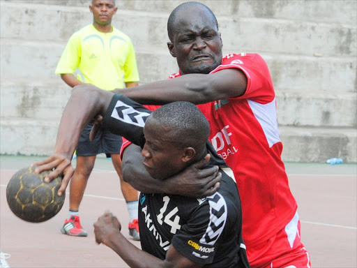 Mark Omala (R) of Ulinzi fights for the ball with Technical University’s Clarence Oyulu during a past handball match at Nyayo court. /FILE