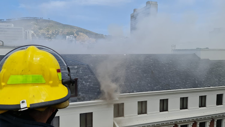 Smoke billows from the roof as firefighting efforts to contain the blaze continue at parliament in Cape Town