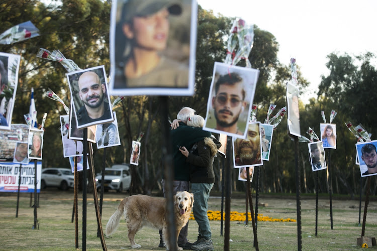 A couple hug near photos of victims killed during Hamas' October 7 attack on civilians attending the Nova music festival in Israel. Israel has accused South Africa of siding with Hamas in its repeated petitions to the International Court of Justice.