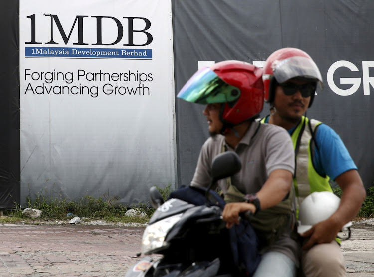Motorcyclists pass a 1MDB billboard at the Tun Razak Exchange development in Kuala Lumpur, Malaysia on February 3 2016. Picture: REUTERS/OLIVIA HARRIS