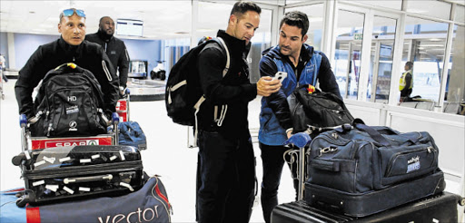 ROLLING IN: Titans head coach Mark Boucher, centre, shows Proteas Test opening batsman Dean Elgar something on his phone while Henry Davids, left, walks through the terminal on the team’s arrival in East London Picture: SISIPHO ZAMXAKA