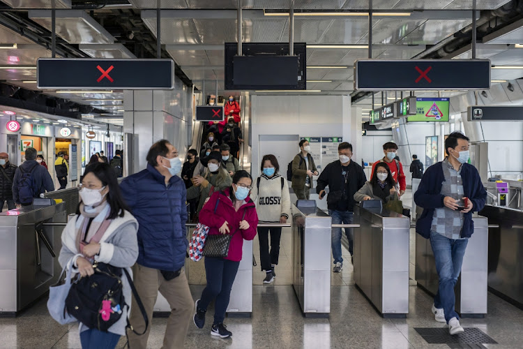 Commuters exit a subway station in Hong Kong, China, on Thursday, February 24, 2022. Hong Kong requires at least one vaccine against Covid-19 to enter most public venues from malls to schools and restaurants, widening its vaccine bubble to stem the spread of the contagious omicron variant.