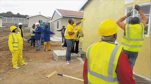 HARD WORK: Human settlements MEC Helen Sauls-August takes a break from painting houses at Kenton-on-Sea to be handed over today Picture: DAVID MACGREGOR