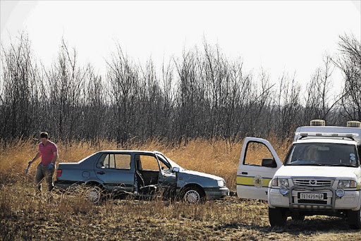 An investigator walks past the car of Duncan Allan, a Tuks student who went missing three weeks ago. His body was found in the car