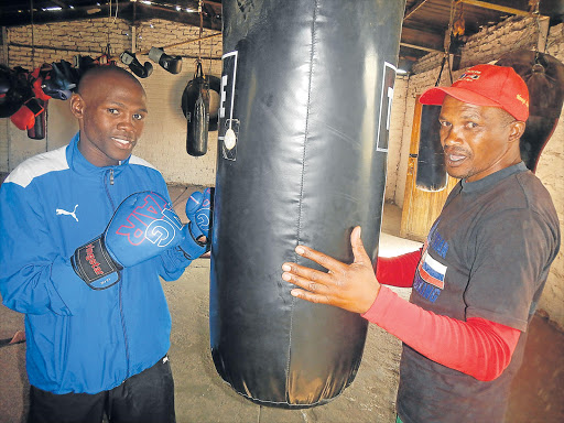 HONING A BAG OF TRICKS: Talented Mthatha-born amateur boxer Sikho Nqothole, 20, gets last-minute instructions from his proud coach Mthetho Dumezweni prior to leaving for Johannesburg yesterday Picture: SIKHO NTSHOBANE