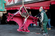 The broken sails of the Moulin Rouge's red windmill are taken away after they fell off during the night in Paris.