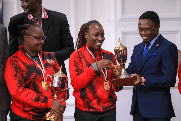Sports Cabinet Secretary Ababu Namwamba holding cup with part of the Kenya 3x3 basketball women team