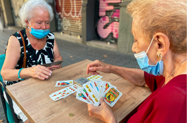 Women play cards at a table along a street in the Eixample district, after Catalonia's regional authorities announced restrictions to contain the spread of the coronavirus disease in Barcelona, Spain on September 20 2020.