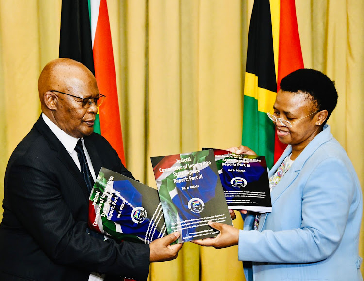 Director-general in the presidency Phindile Baleni receives the nearly 1,000-page third volume of the state capture commission's report on Tuesday from commission secretary Prof Itumeleng Mosala.