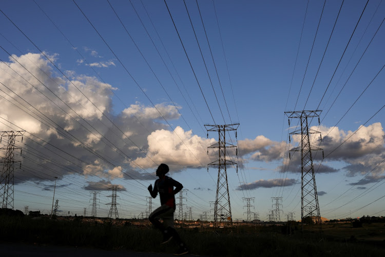 A man jogs below Eskom's electricity pylons in Johannesburg. File photo