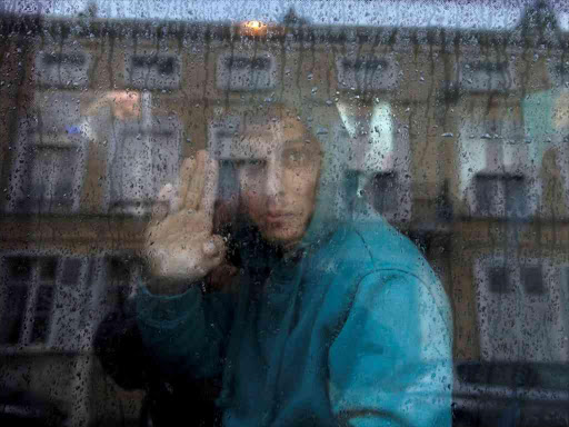 An Afghan adolescent migrant waves from a van as he departs with six others from the emergency shelter for minors in Saint Omer, France as they leave for Britain October 18, 2016. /REUTERS