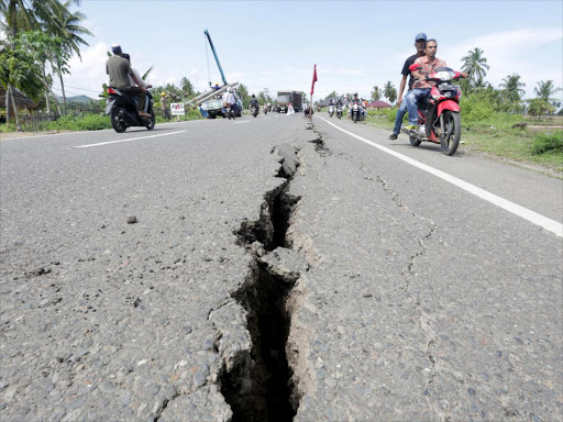Motorcyclists pass a damaged section of a road following an earthquake in Meureudu, Pidie Jaya, in the northern province of Aceh, Indonesia December 7, 2016 in this photo taken by Antara Foto. A 7.7 magnitude quake has also hit the Solomon Islands, December 8, 2016. /REUTERS