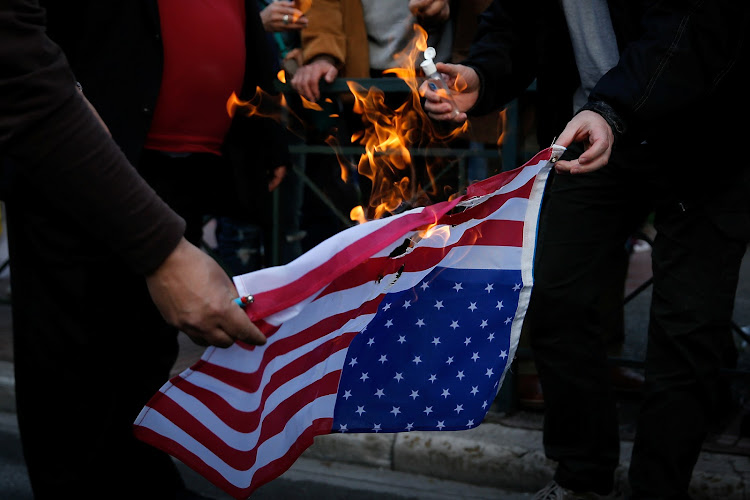 Protesters burn an US flag during a demonstration outside the US embassy against air strikes carried out in Syria, in Athens, Greece, April 14, 2018.